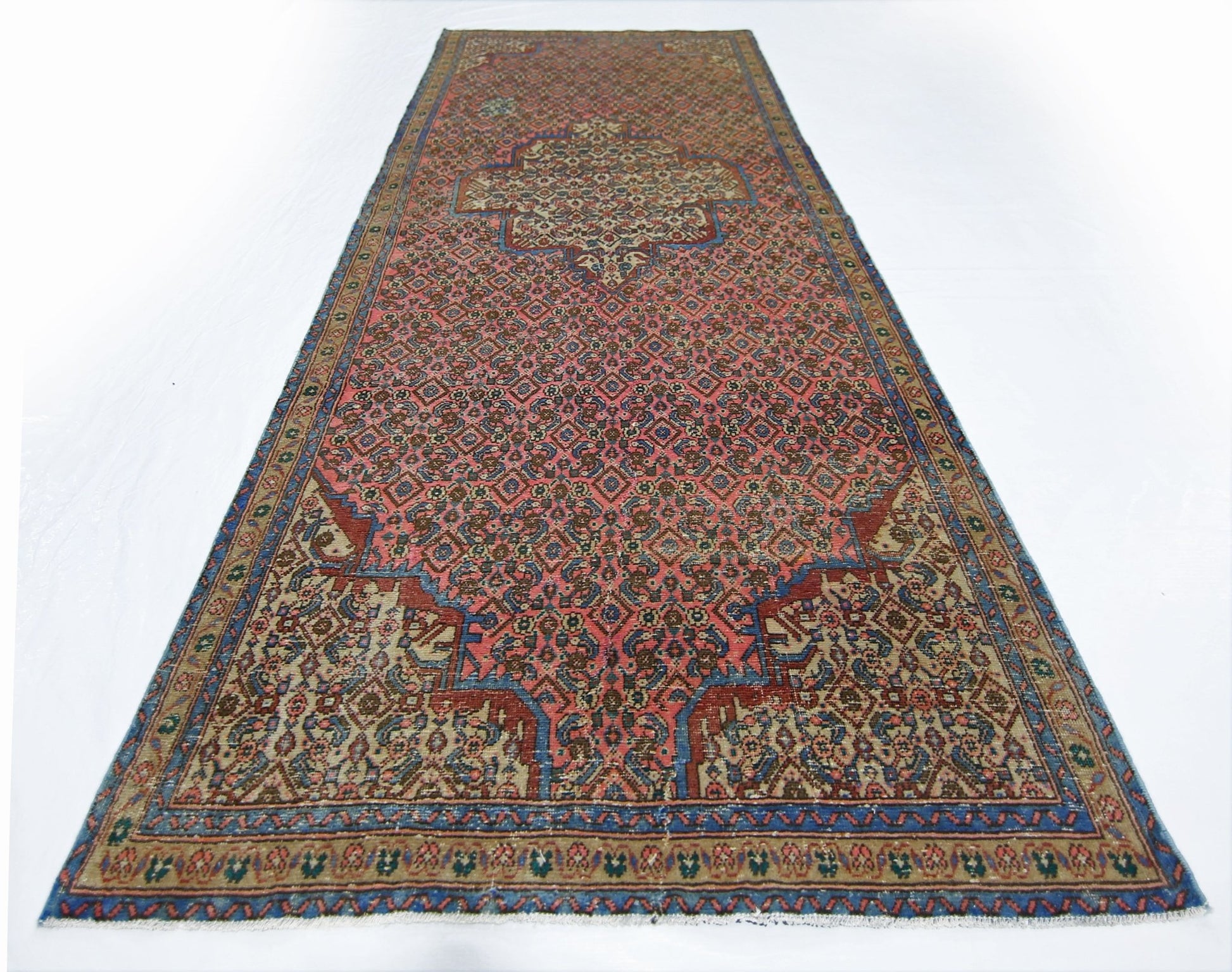 A vintage Persian Senneh runner featuring a geometric pattern in red, blue, and beige tones.
