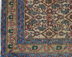 A vintage Persian Senneh runner featuring a detailed floral pattern in blue, pink, and brown tones.