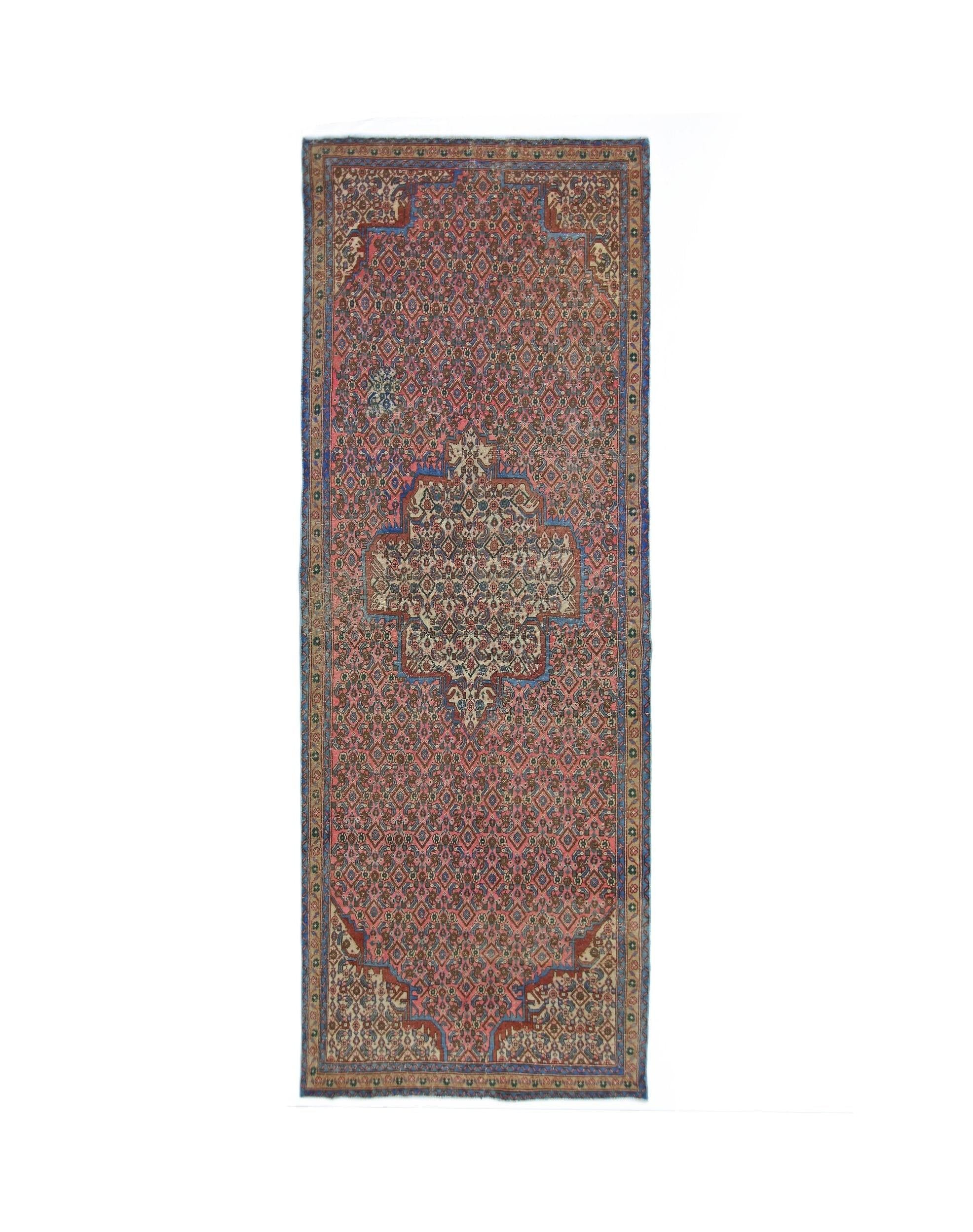 A vintage Persian Senneh runner featuring a central medallion on a patterned rose-colored field.