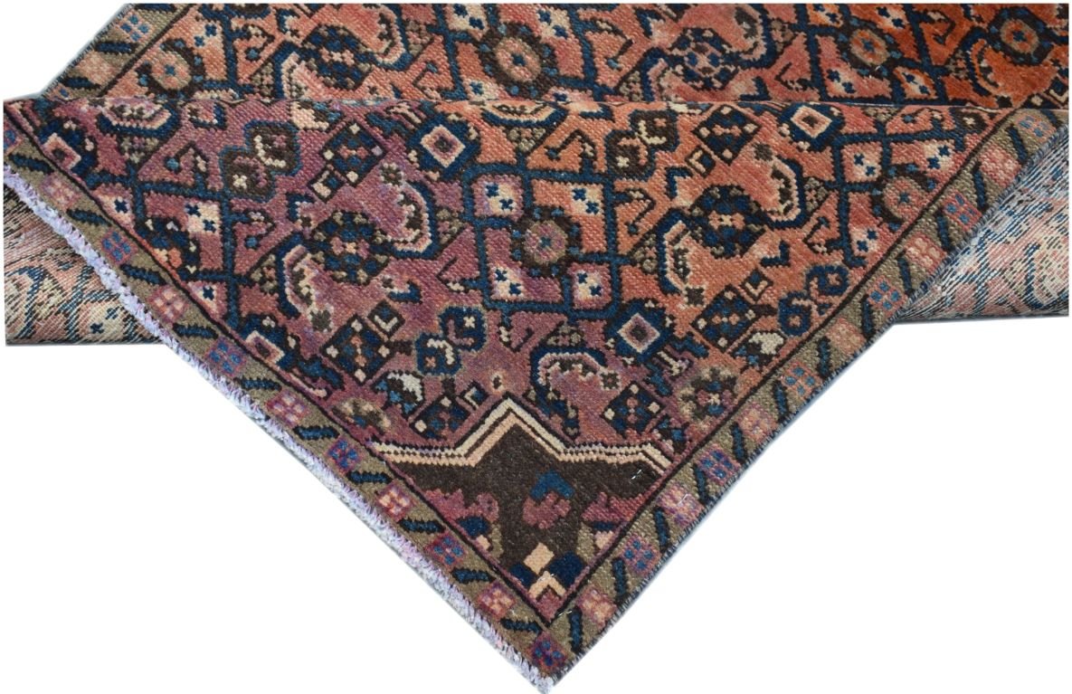 A vintage Persian Senneh runner featuring a geometric pattern in shades of red, blue, and brown.