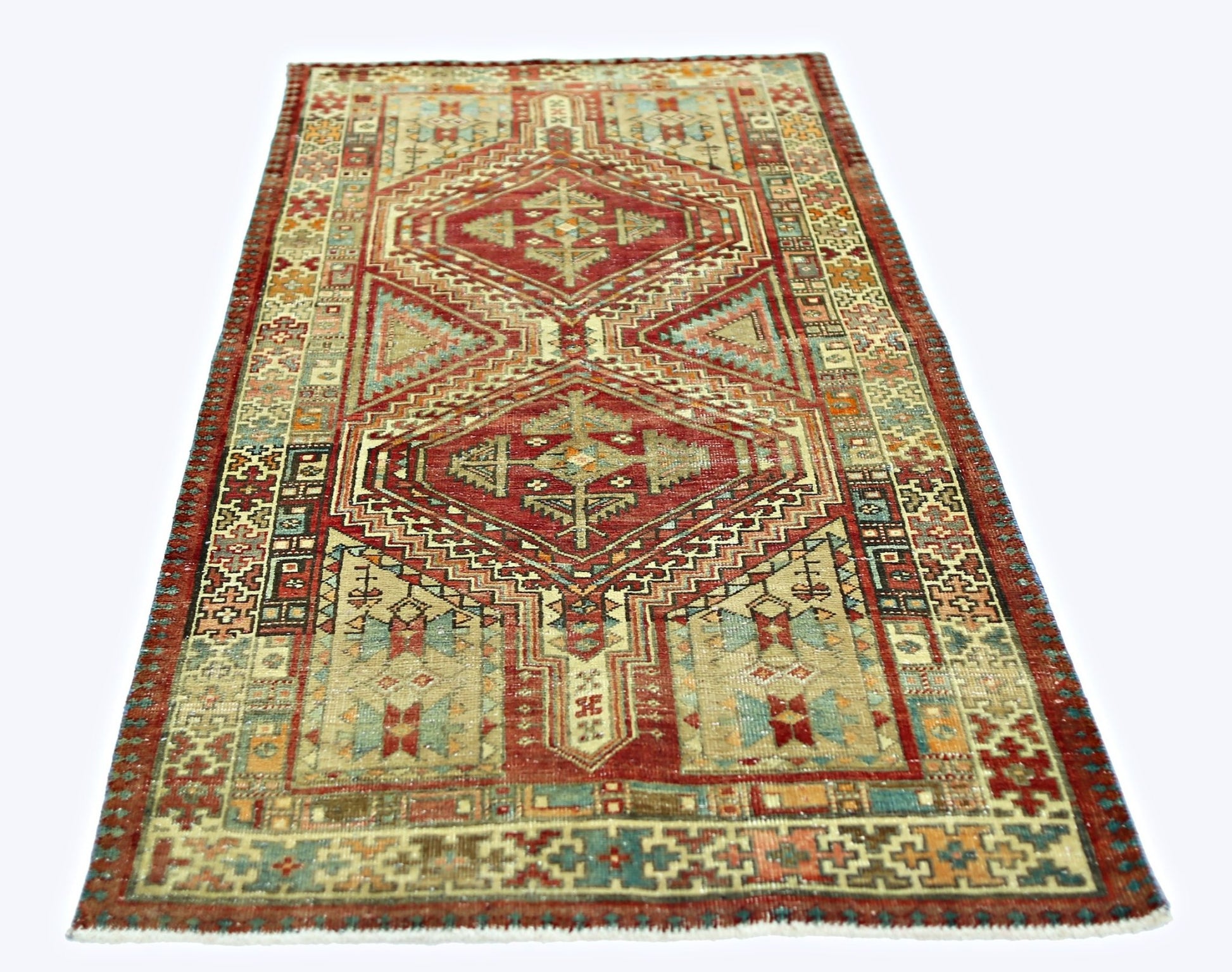 A rectangular vintage Persian rug featuring geometric diamond patterns in red, blue, and beige.