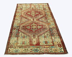 A rectangular vintage Persian rug featuring geometric diamond patterns in red, blue, and beige.