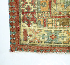 A close-up of a vintage Persian rug featuring geometric patterns in red, green, and orange tones.