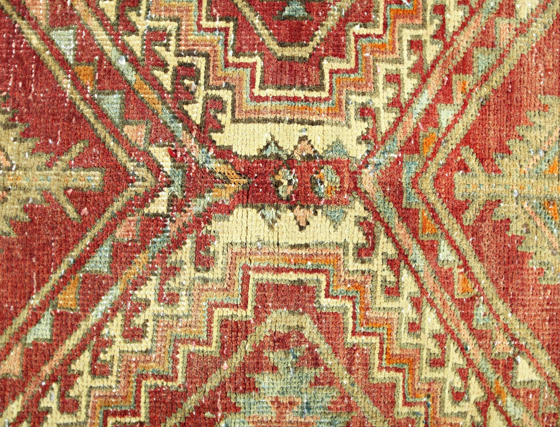 A vintage Persian rug featuring a geometric pattern in shades of red, cream, and green.