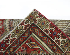 A corner of a vintage Persian Serab runner showing intricate geometric patterns in red and brown.