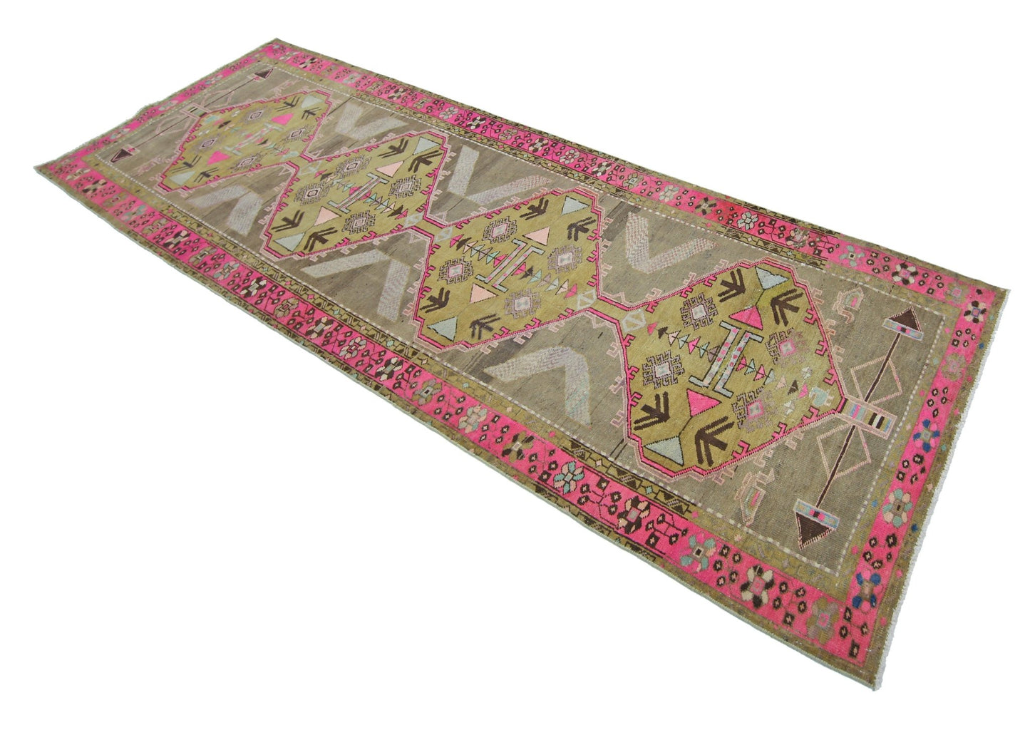 A vintage Persian Serab runner featuring geometric medallions in pink, green, and brown tones.