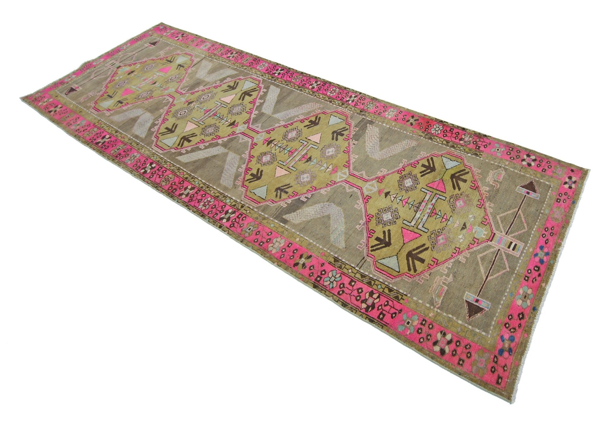 A vintage Persian Serab runner featuring geometric medallions in pink, green, and brown tones.