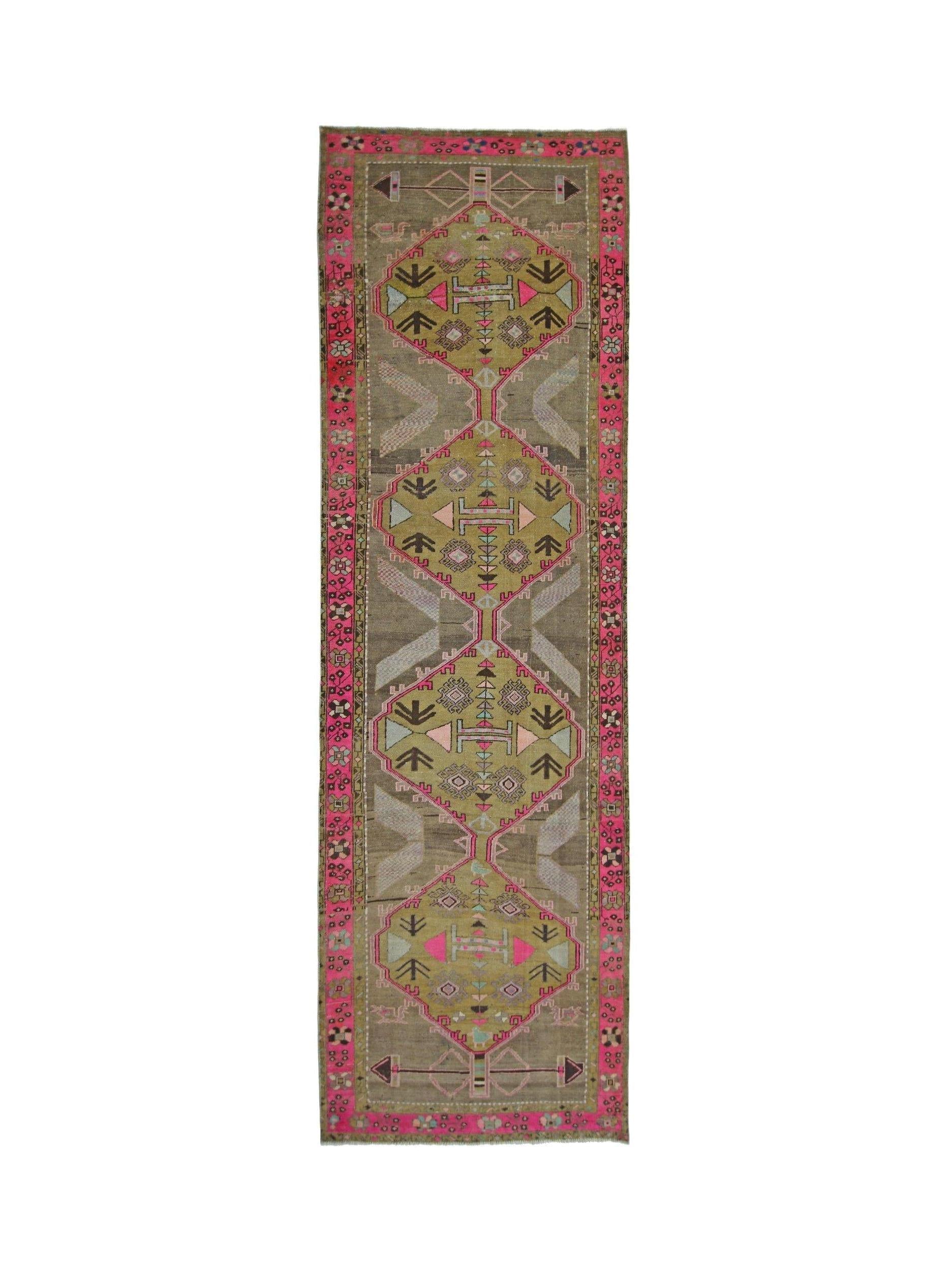 A vintage Persian Serab runner featuring geometric medallions in pink, green, and brown tones.