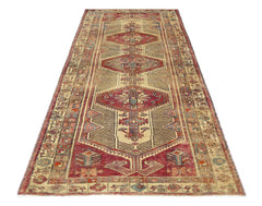 A vintage Persian Serab runner featuring a geometric medallion pattern in red and beige tones.