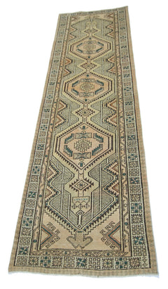 A vintage Persian Serab runner rug featuring geometric diamond patterns in muted earth tones.