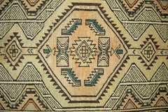 A vintage Persian Serab runner featuring a geometric pattern in tan, brown, and teal wool.