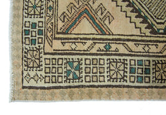 A close-up of a vintage Persian Serab runner featuring geometric patterns in brown, beige, and green.