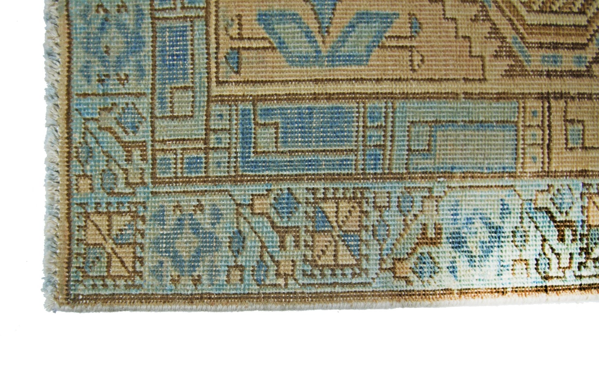 A corner detail of a vintage Persian Serab runner featuring geometric patterns in blue and tan.