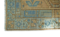 A corner detail of a vintage Persian Serab runner featuring geometric patterns in blue and tan.
