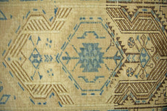 A vintage Persian Serab runner featuring geometric blue and brown patterns on a tan wool base.