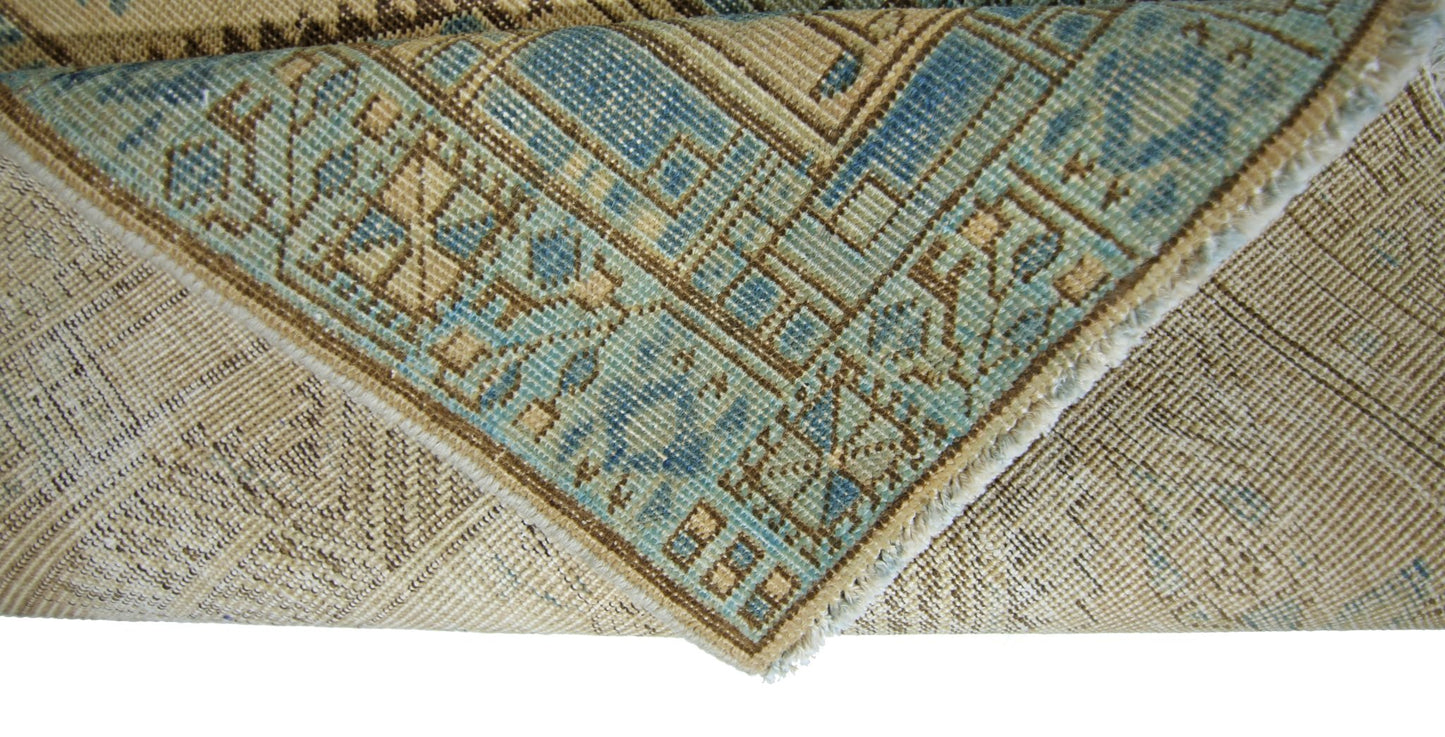 A corner of a vintage Persian Serab runner showing a blue and beige geometric pattern.