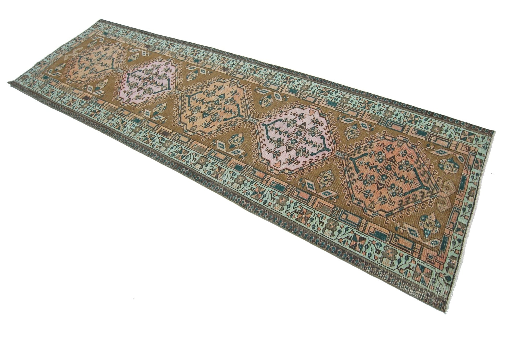A vintage Persian Serab runner rug featuring geometric medallions in muted earth tones and pink.