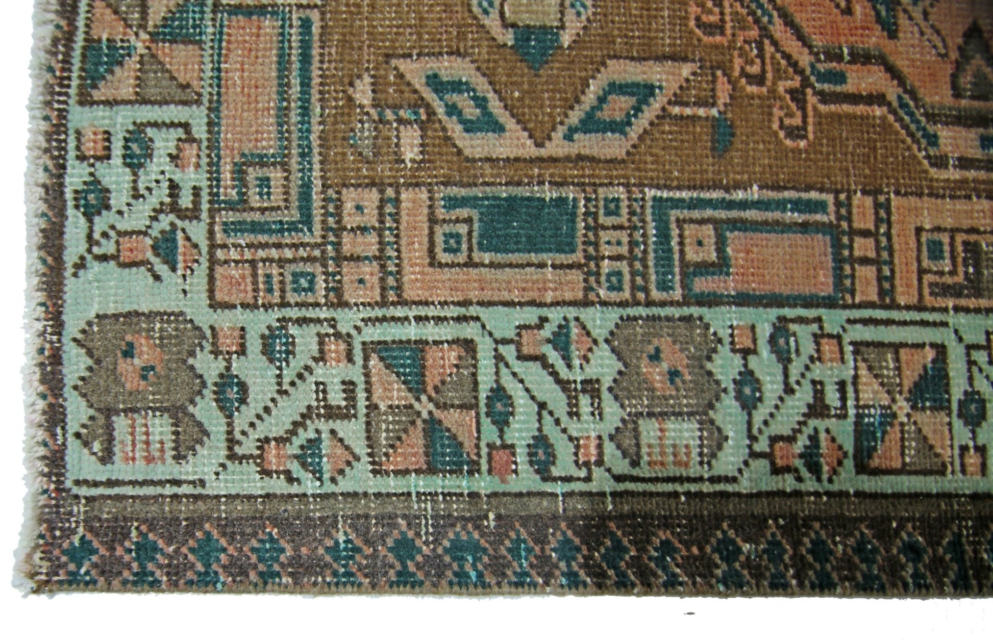 A vintage Persian Serab runner featuring geometric patterns in shades of brown, teal, and peach.