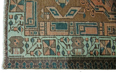 A vintage Persian Serab runner featuring geometric patterns in shades of brown, teal, and peach.