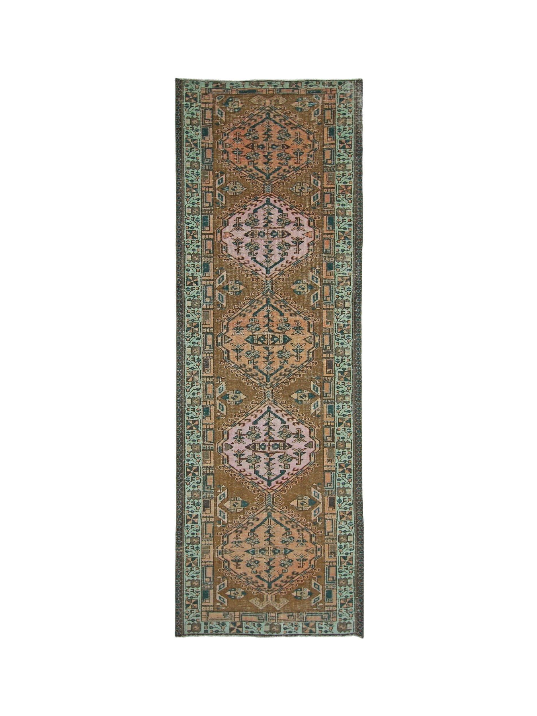 A vintage Persian Serab runner rug featuring geometric medallions in pink and brown tones.