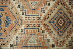 A vintage Persian Serab runner featuring geometric diamond patterns in blue, tan, and cream.