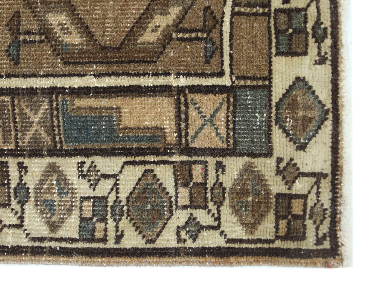 A corner detail of a vintage Persian Serab runner featuring geometric patterns in earth tones.