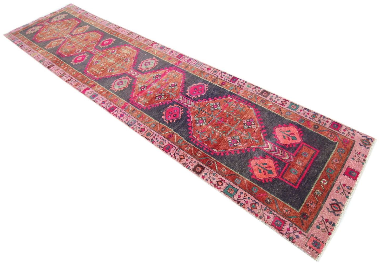 A vintage Persian Hamadan runner featuring geometric medallions in orange and pink on a dark field.