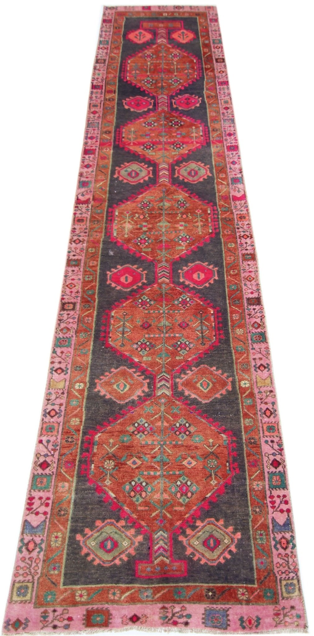 A vintage Persian Hamadan runner featuring geometric medallions in red and pink on a dark field.