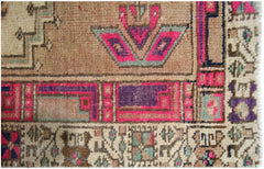 A close-up of a vintage Persian Hamadan runner featuring geometric floral motifs in pink and purple.