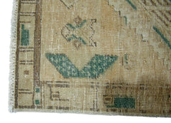 A close-up of a vintage Persian Serab runner featuring a geometric pattern in tan and green.