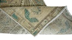 A folded vintage Persian Serab runner featuring geometric patterns in beige, brown, and green.