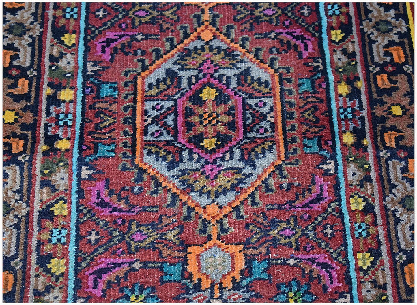 A handwoven vintage Persian Shiraz rug featuring a central medallion in red, blue, and orange.