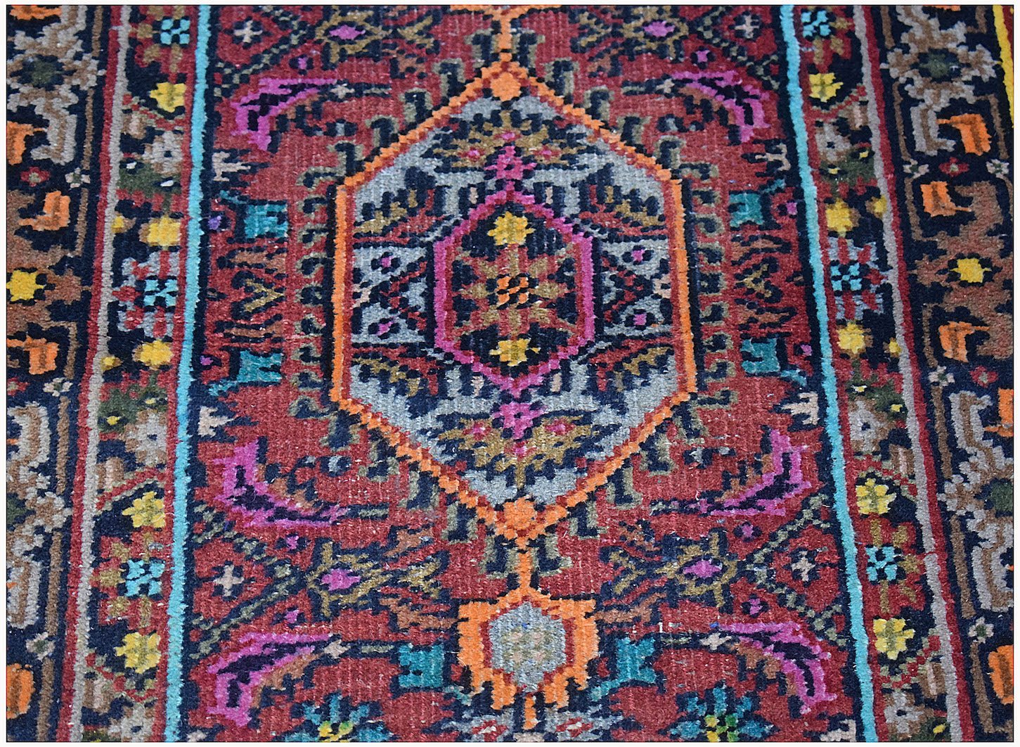 A handwoven vintage Persian Shiraz rug featuring a central medallion in red, blue, and orange.