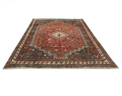 A handwoven vintage Persian Shiraz rug featuring a geometric medallion on a red field.