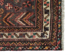 A close-up of a vintage Persian Shiraz rug featuring intricate geometric patterns in wool.