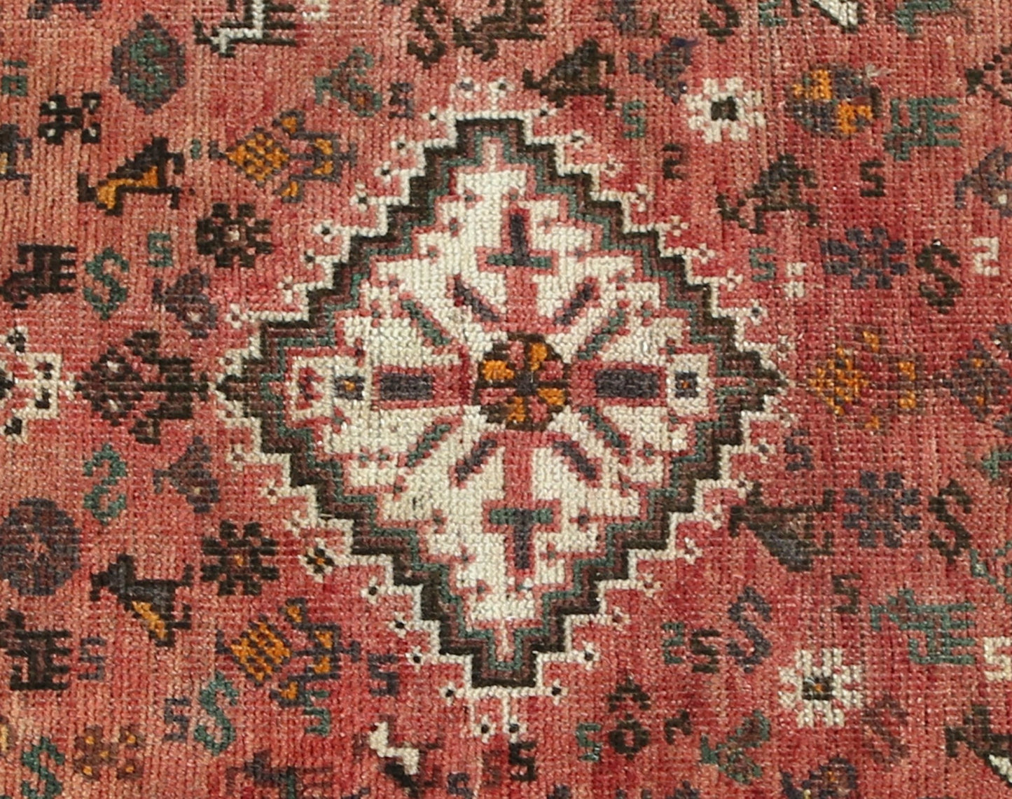 A vintage handwoven Persian Shiraz rug featuring a central white diamond motif on a red field.