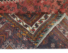 A corner of a handwoven vintage Persian Shiraz rug showing its intricate geometric patterns.