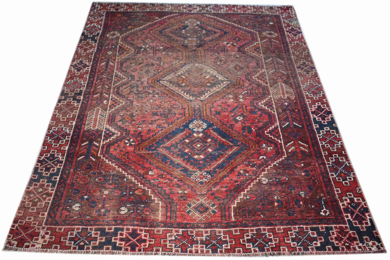 A handwoven vintage Persian Shiraz rug featuring a geometric diamond pattern in red and blue.
