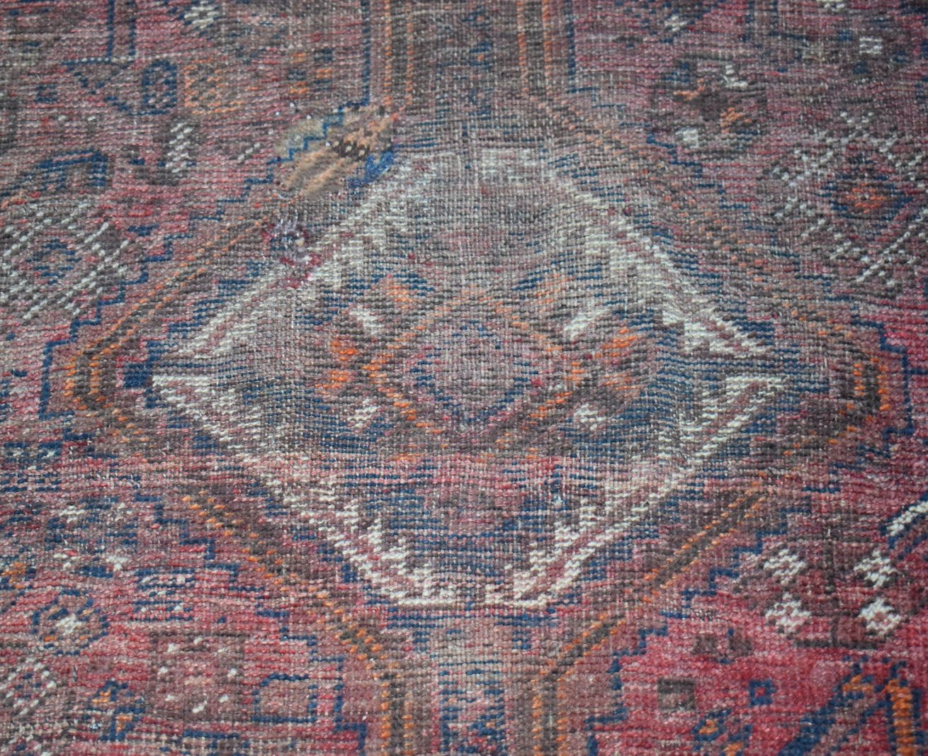 A vintage handwoven Persian Shiraz rug featuring a central diamond medallion in red and blue tones.