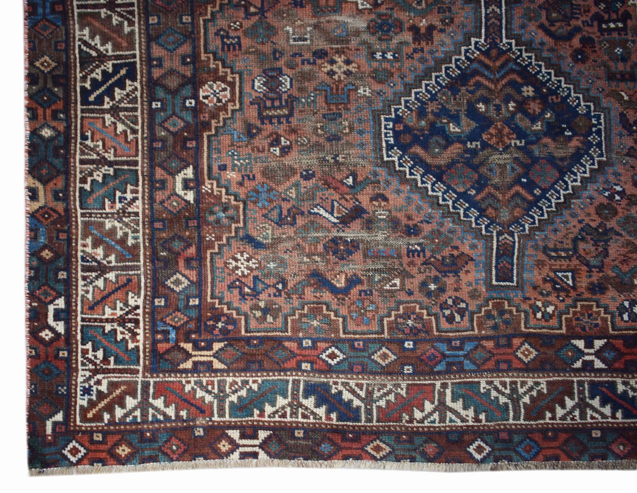 A vintage handwoven Persian Shiraz rug featuring a geometric medallion on a rust-colored field.