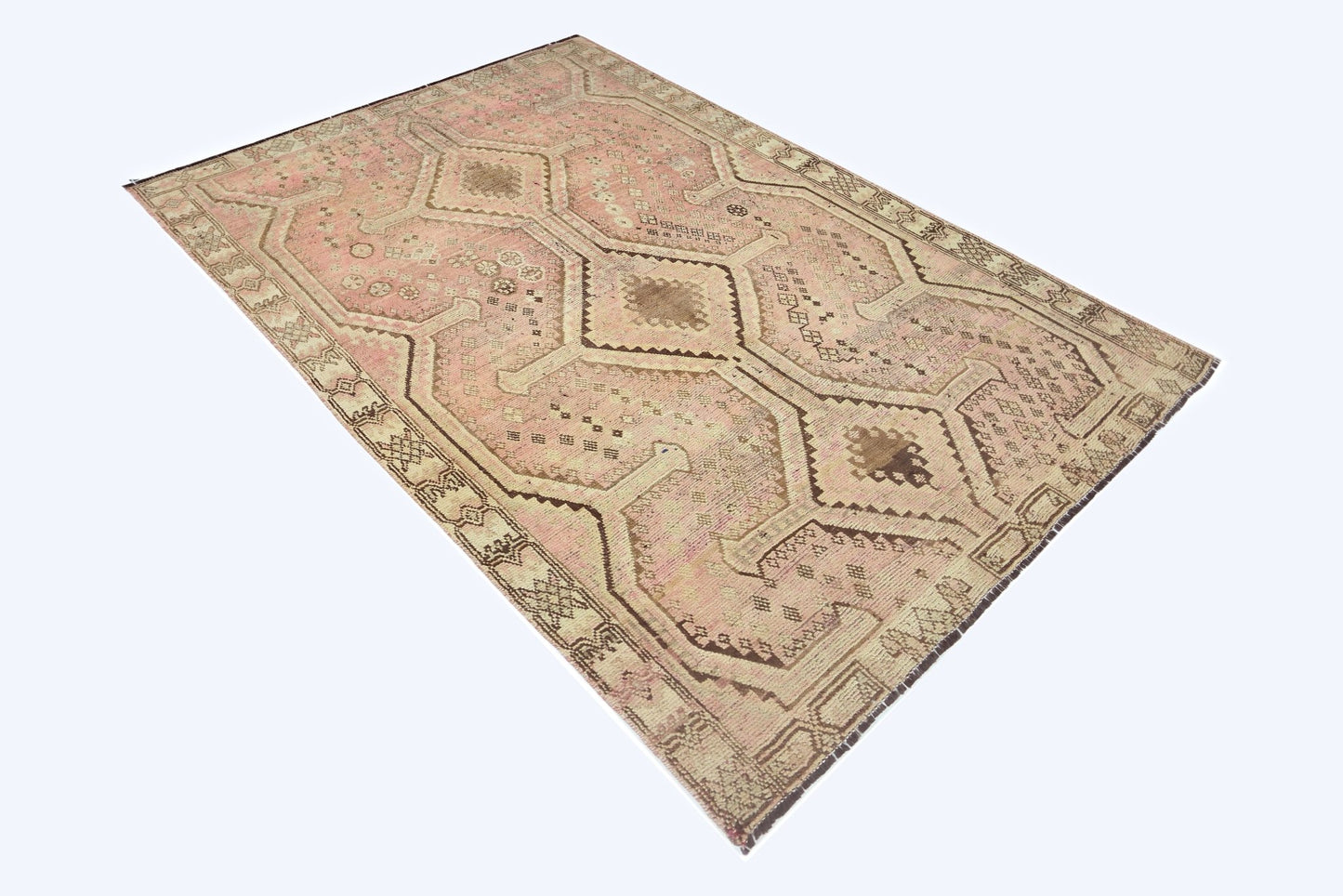 A vintage Persian Shiraz rug featuring a geometric pattern in shades of pink and brown.