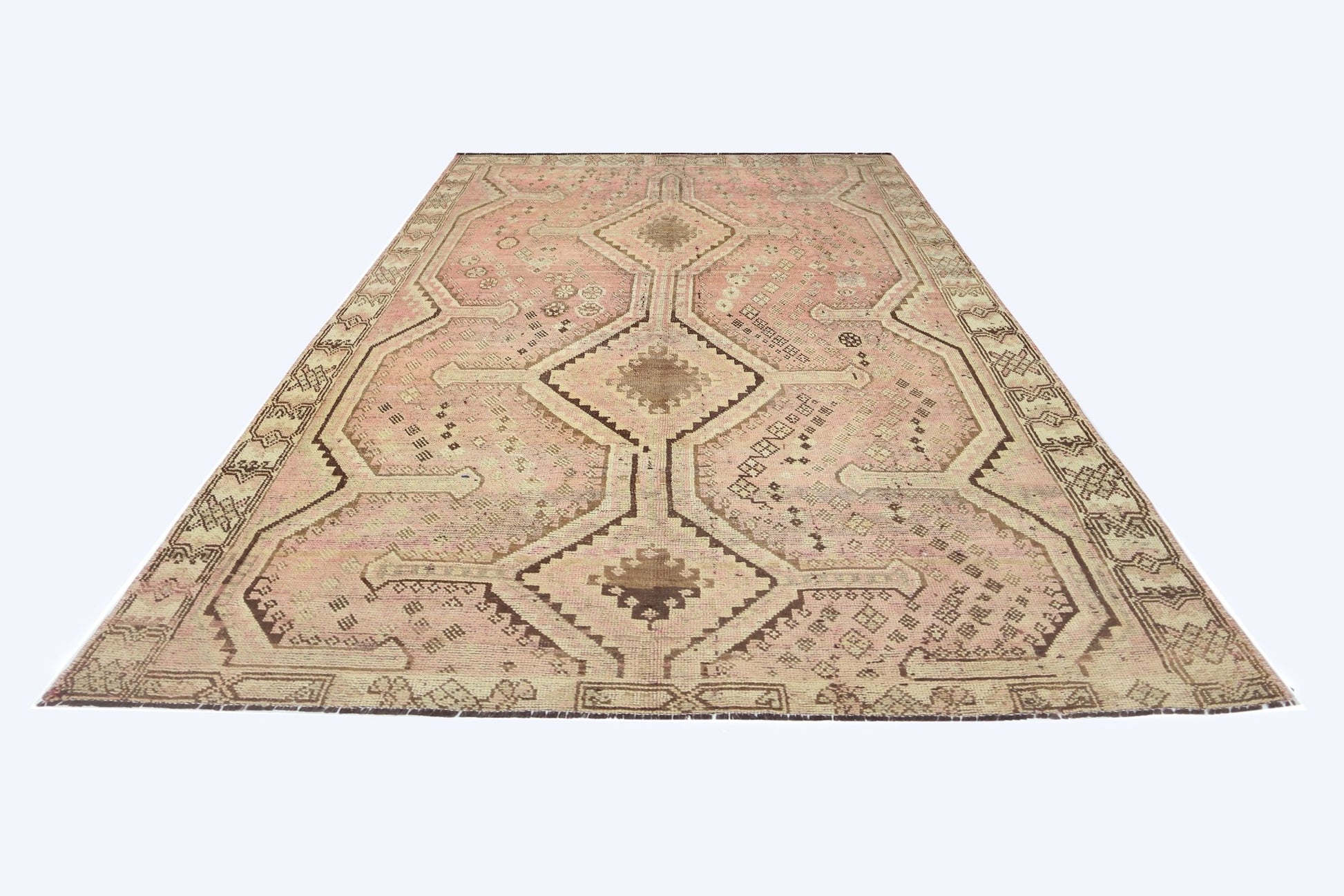 A vintage Persian Shiraz rug featuring a geometric diamond pattern in faded pink and brown tones.