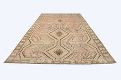 A vintage Persian Shiraz rug featuring a geometric diamond pattern in faded pink and brown tones.