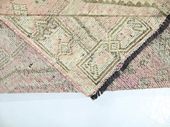 A corner of a vintage Persian Shiraz rug folded over to show its pink and beige patterned wool.