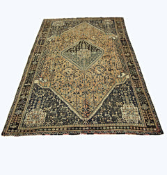 A vintage handmade Persian Shiraz rug featuring a central diamond medallion on a tan and dark field.