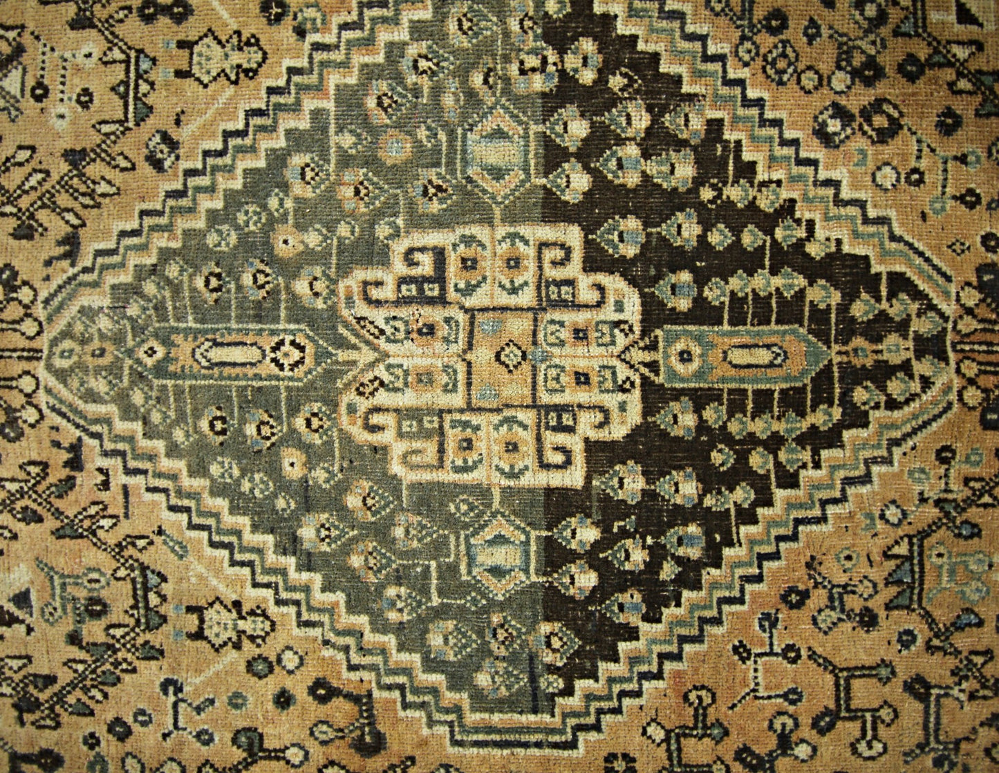 A vintage Persian Shiraz rug featuring a geometric diamond medallion in shades of brown and tan.