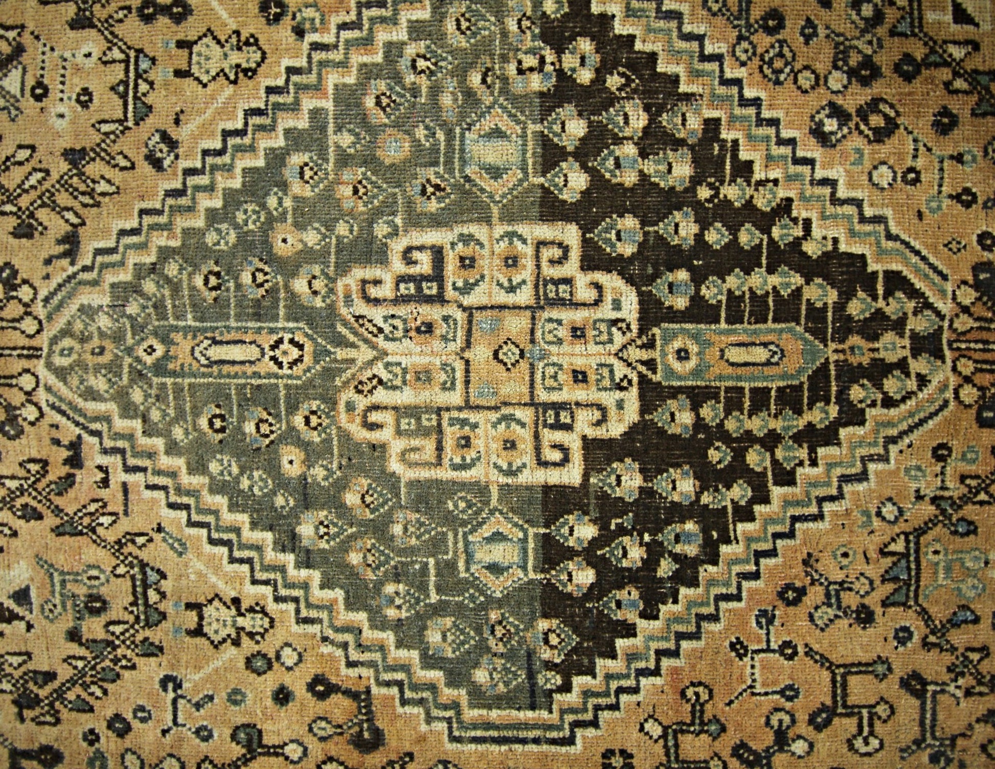 A vintage Persian Shiraz rug featuring a geometric diamond medallion in shades of brown and tan.