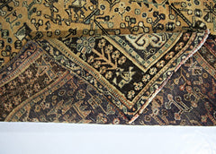 A corner of a vintage Persian Shiraz rug is folded back to reveal its intricate wool pattern.