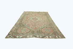 A vintage Persian Shiraz rug featuring a central diamond medallion on a muted pink and brown field.