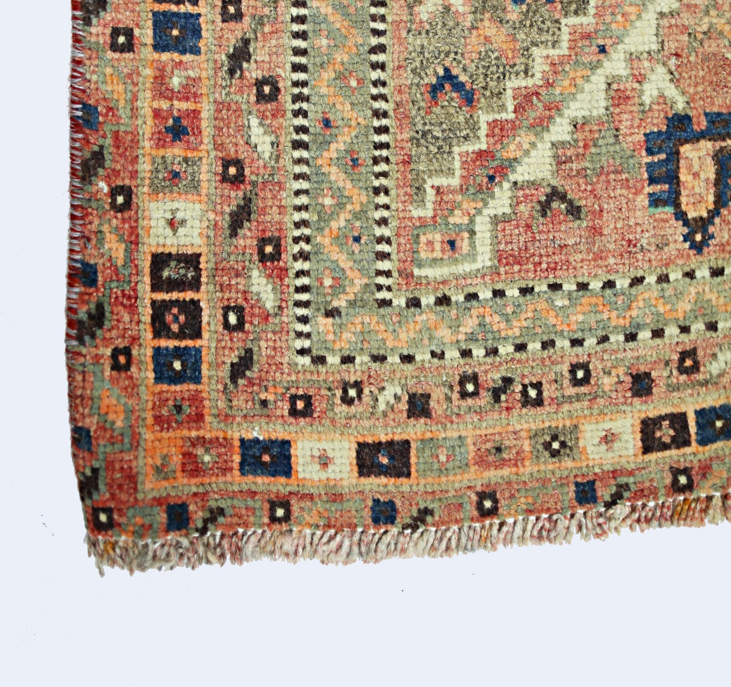 A corner view of a vintage Persian Shiraz rug featuring geometric patterns in red, blue, and tan.